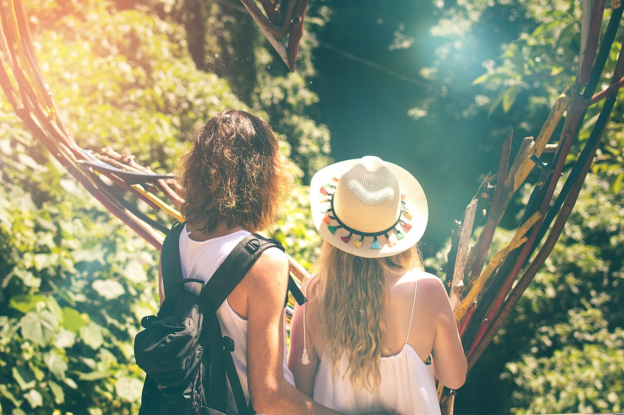 Two travellers with backpacks on a path surrounded by greenery.