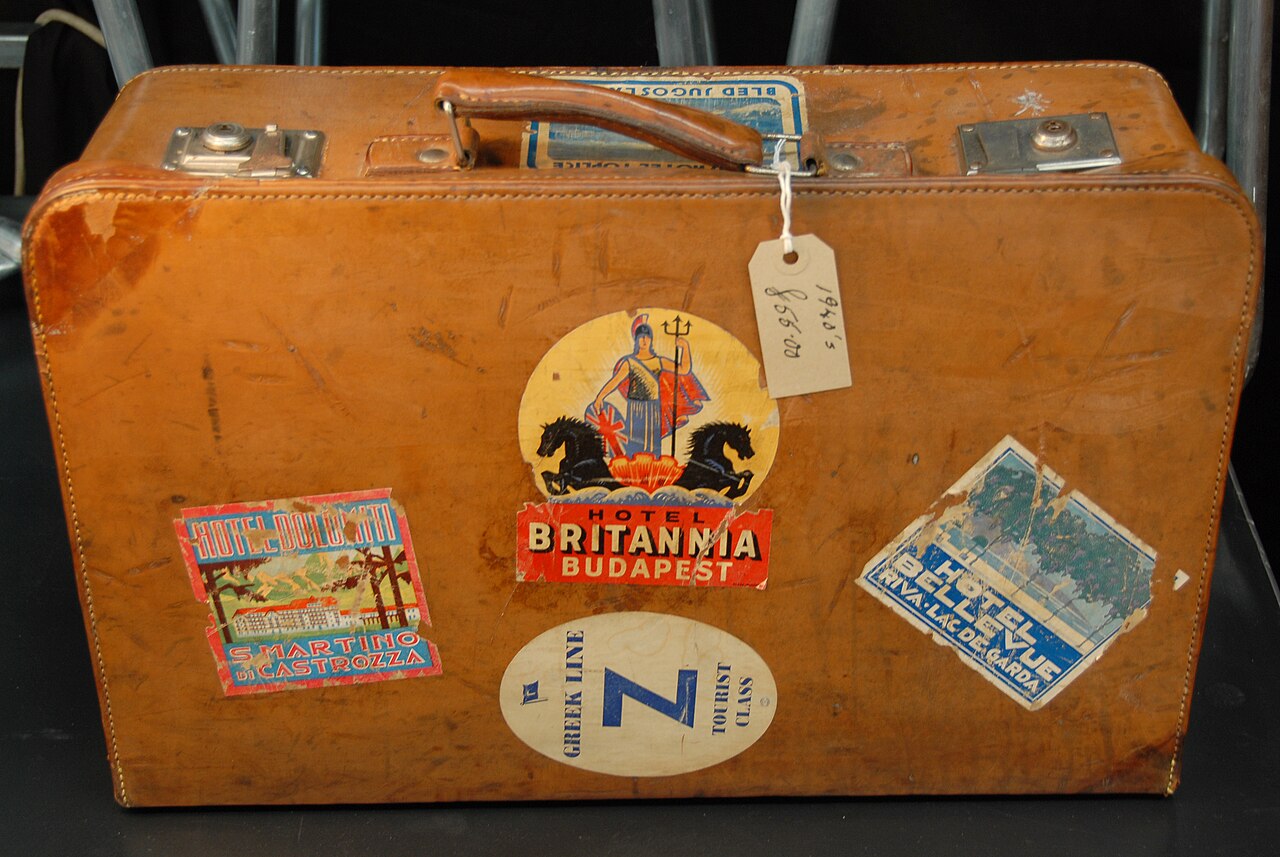 A vintage suitcase covered with destination labels.