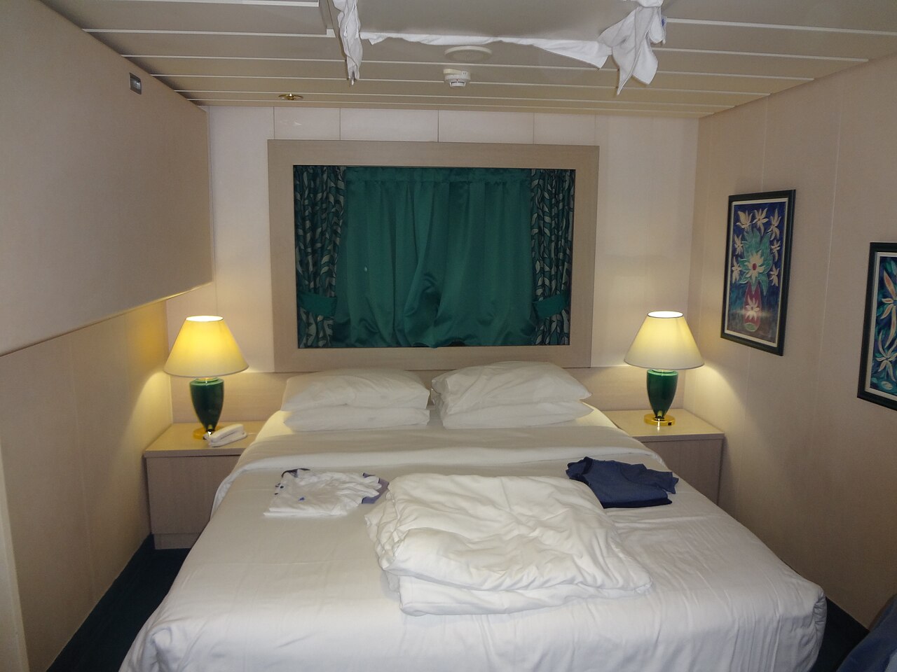 A cruise cabin interior with a bed and two reading lamps.