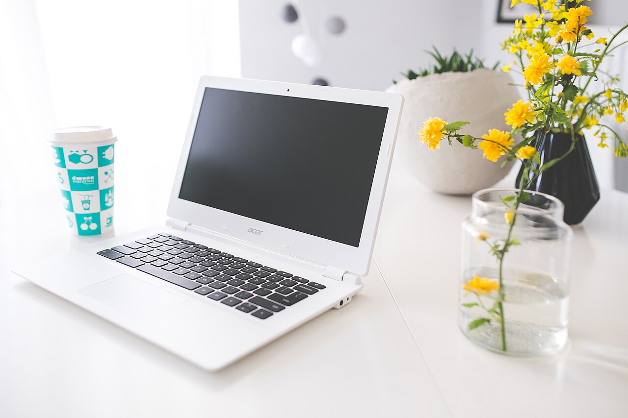 A laptop and notebook on a bright desk.