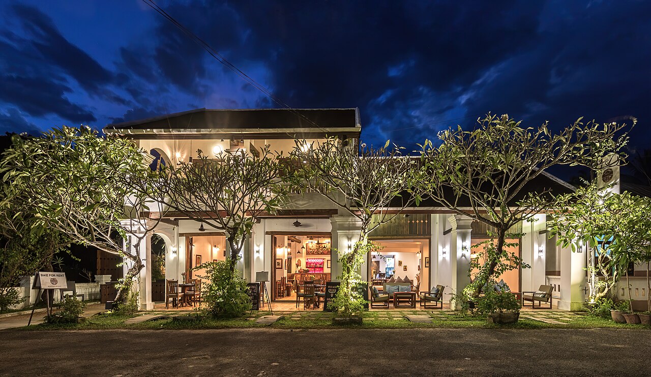 An illuminated accommodation building and garden beneath an evening sky.