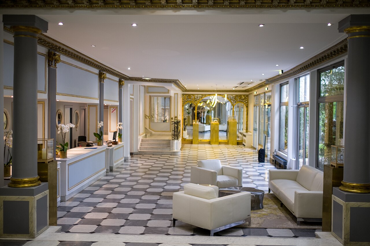 An ornate hotel reception area with seating and a front desk.