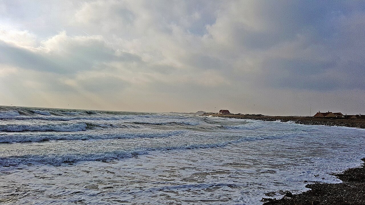 Waves along a windy shore beneath a cloudy sky.