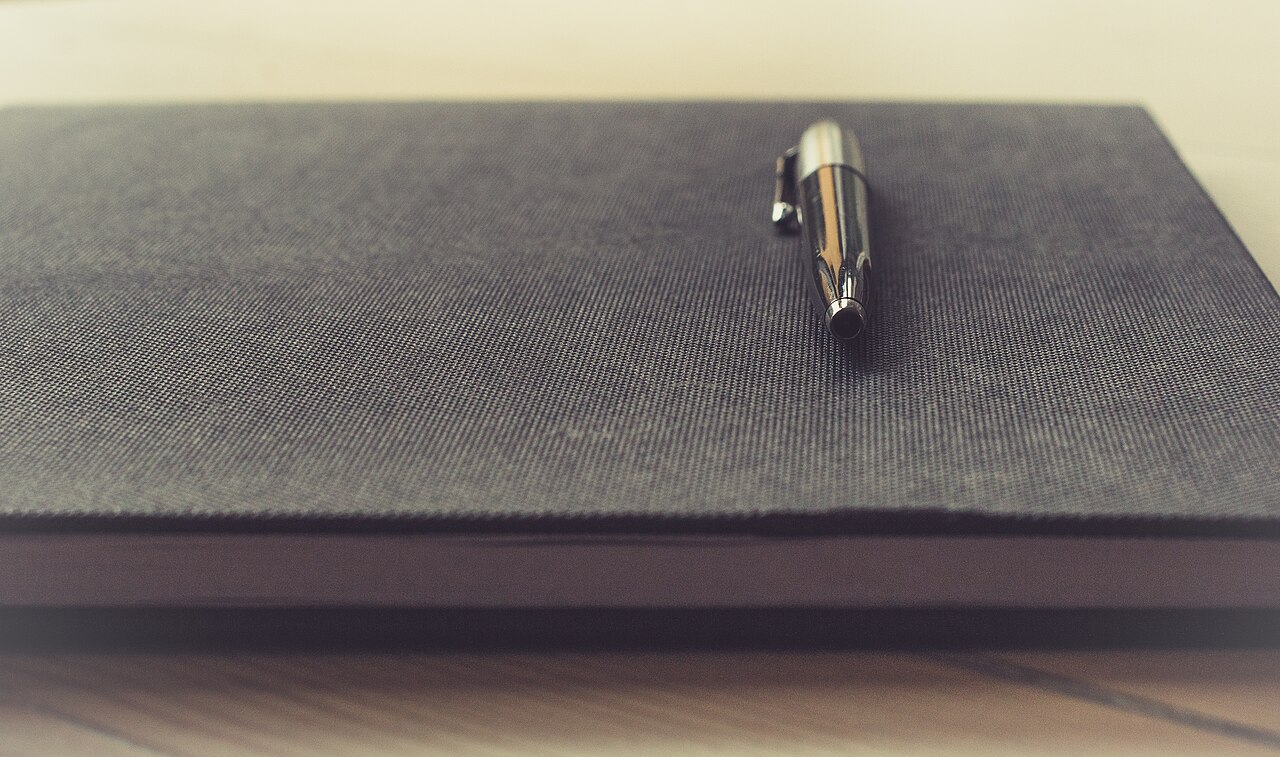 A pen resting on the fabric cover of a notebook.