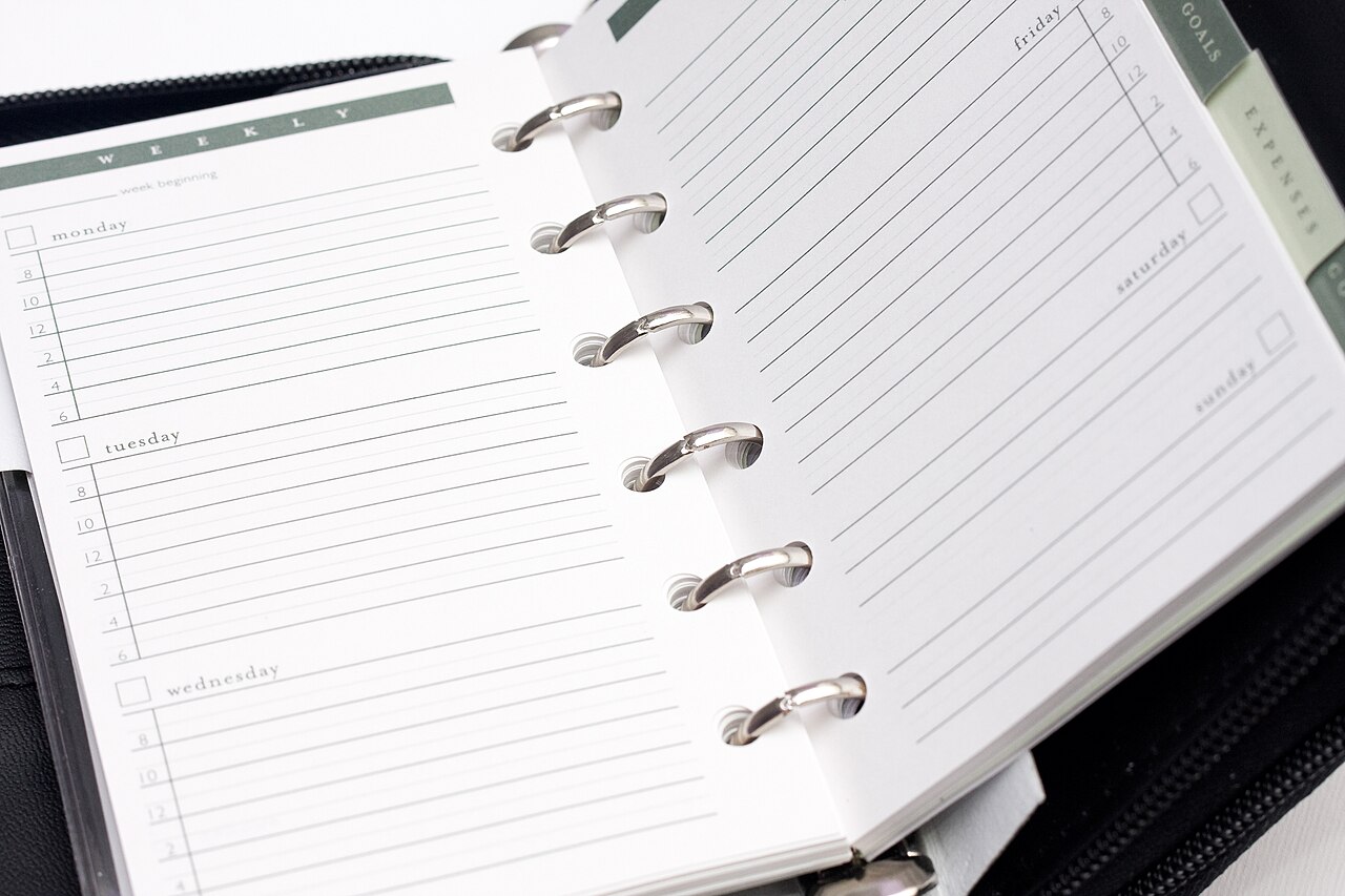 An open ring-bound planner with ruled scheduling pages.